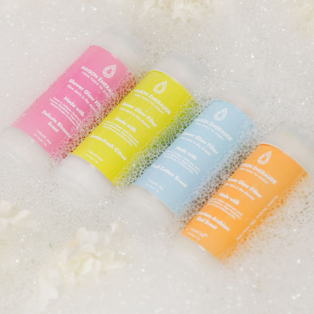 Four Maison Émeraude Shower Glow Filters in foam, showcasing Blossom, Citrus, Cotton, and Oud fragrance scents